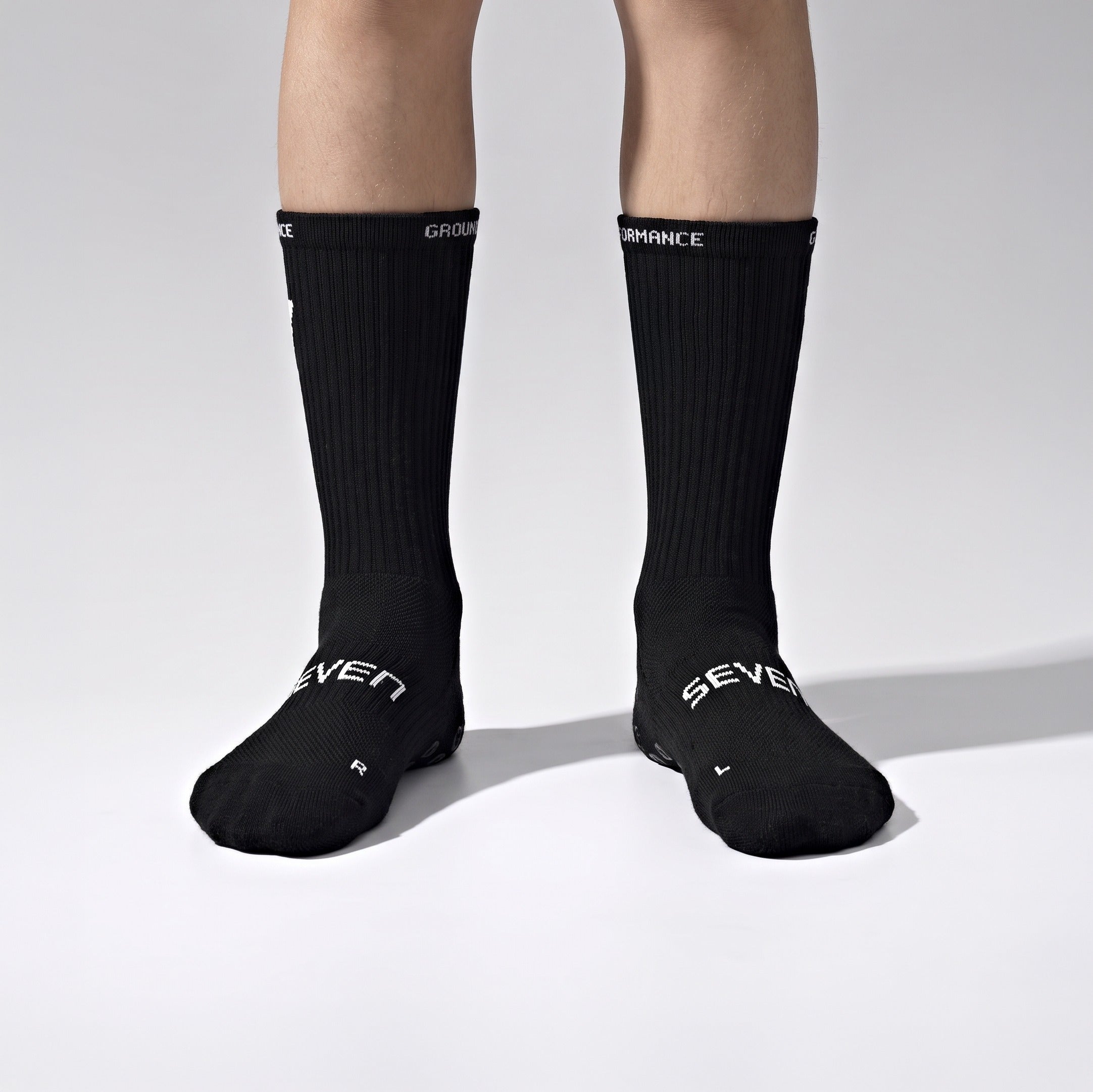 Seven junior black grip performance socks, both feet quarter view