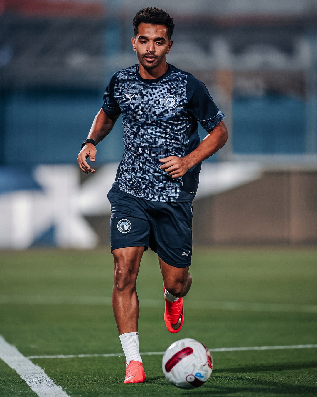 Professional footballer running with the ball in training in white Seven performance socks